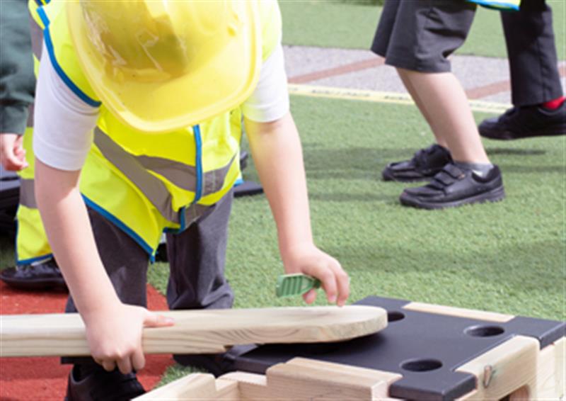 Child lifting a Play Builder Plank and fixing it into place on a Block.
